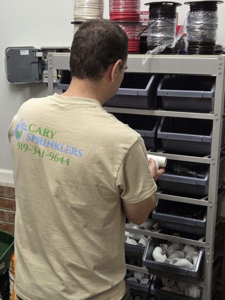 Cary Sprinklers team member in a branded shirt pulling irrigation wire and parts in the shop