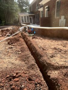 Drainage trench dug along a brick home foundation for water management in Cary, NC