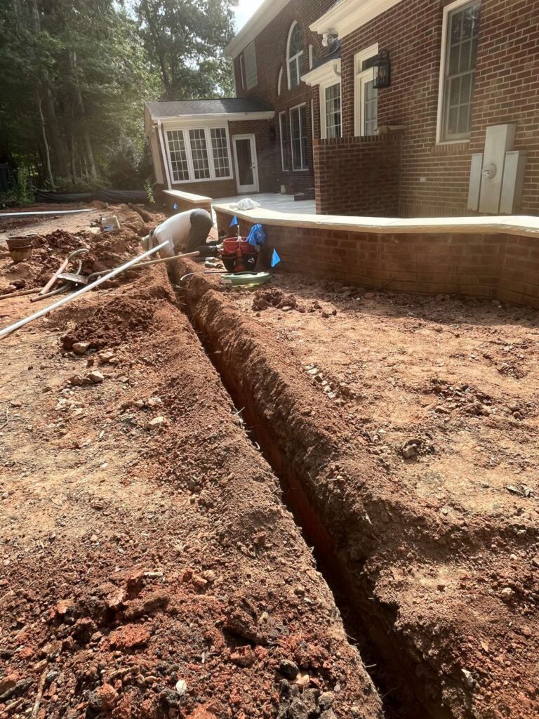Drainage trench dug along a brick home foundation for water management in Cary, NC