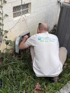 Cary Sprinklers technician mounting an irrigation controller beside a home in Cary, NC