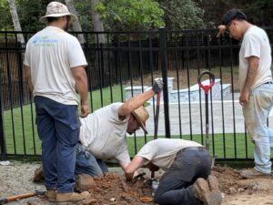 Cary Sprinklers crew installing irrigation along a fence line by a pool in Cary, NC