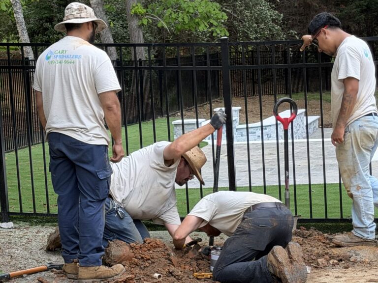 Cary Sprinklers crew installing irrigation along a fence line by a pool in Cary, NC