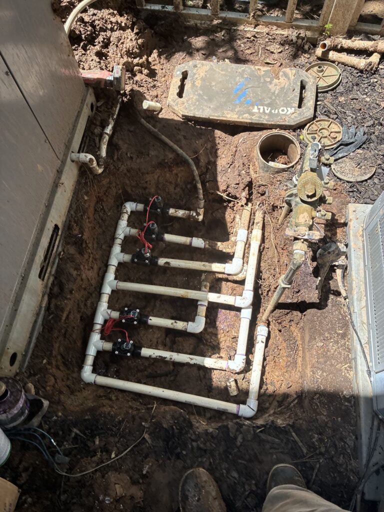 Multi-valve irrigation manifold installed along a foundation in Cary, NC
