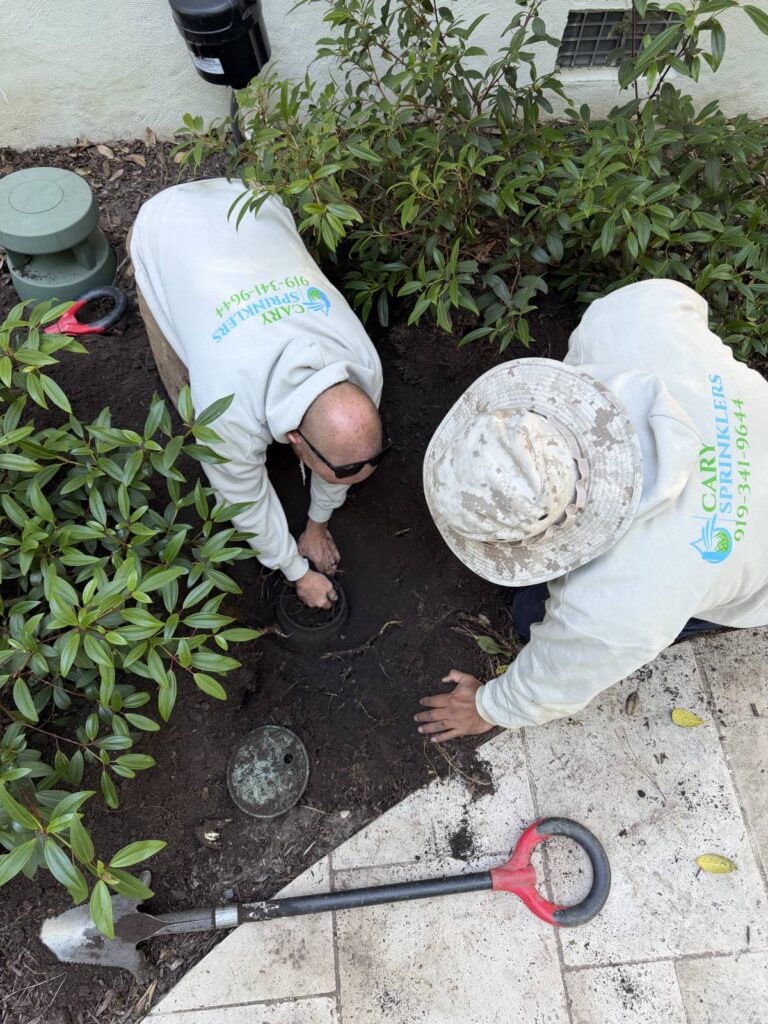 Two Cary Sprinklers technicians working together on an irrigation repair in a Cary, NC yard