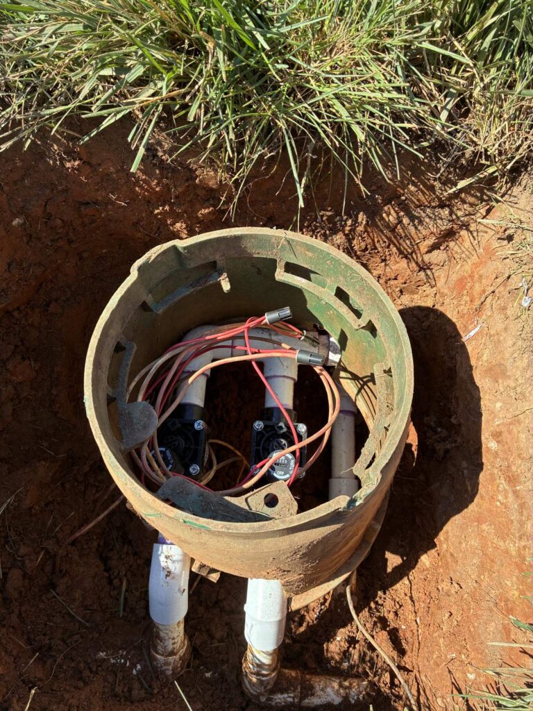 Round irrigation valve box with exposed valve wiring during a repair in the Triangle, NC