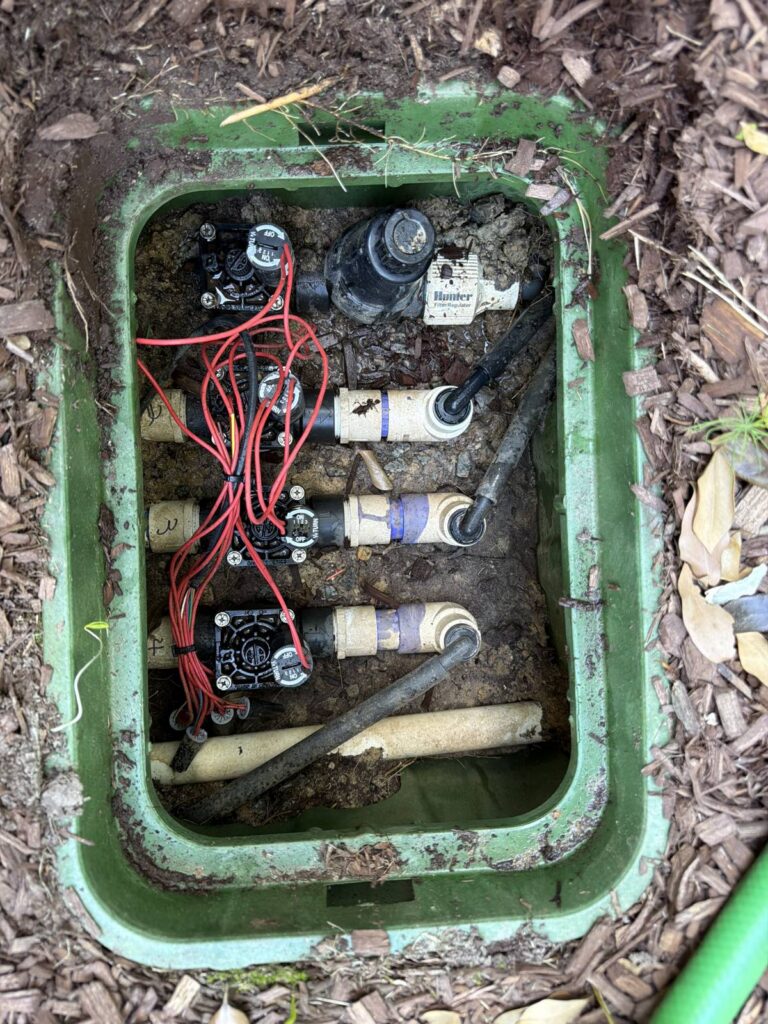 Open irrigation valve box showing a Hunter valve manifold serviced in Cary, NC