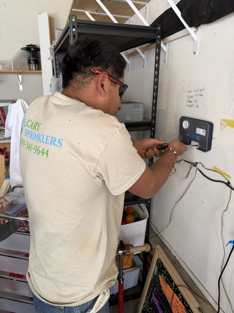 Cary Sprinklers technician wiring a smart irrigation controller on a garage bench in Cary, NC