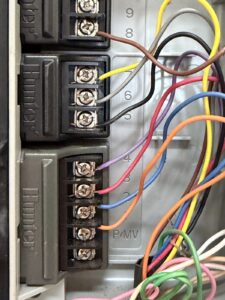 Close-up of color-coded zone wiring landed inside a Hunter irrigation controller in Cary, NC
