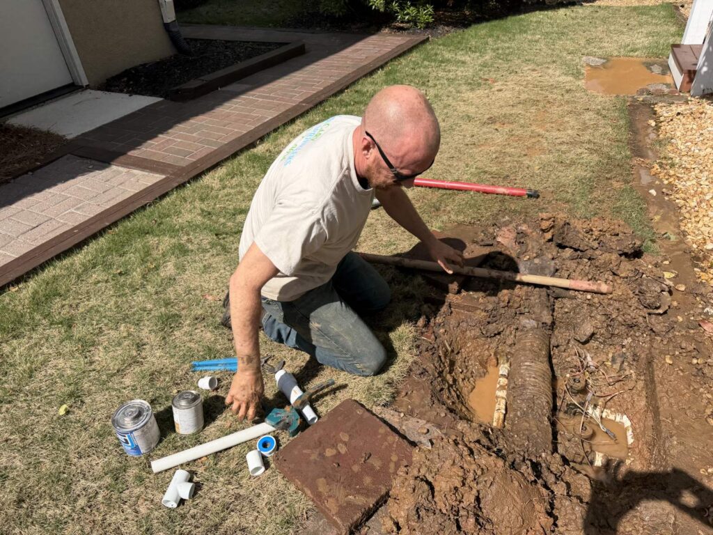 Technician repairing an irrigation mainline near a front walkway in Cary, NC