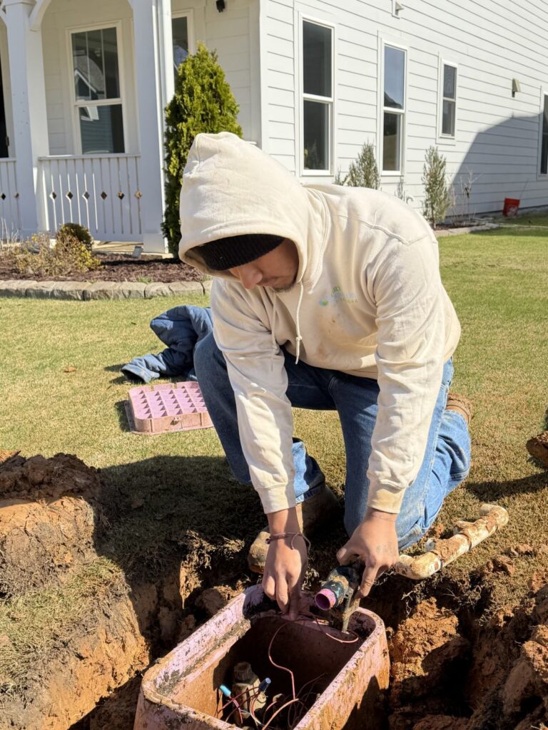 Cary Sprinklers technician installing a new sprinkler zone in a front-yard planting bed in Cary, NC