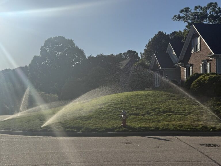 Sprinkler system running at golden hour across a healthy Triangle, NC lawn